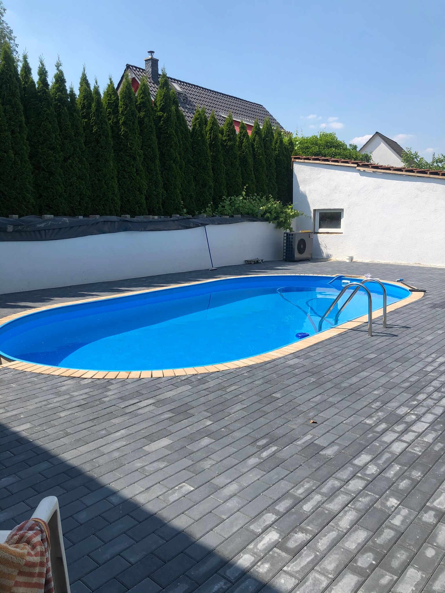 Pflasterarbeiten an einer Poolumrandung im privaten Garten